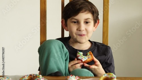 Boy eats homemade glazed sprinkled donuts
