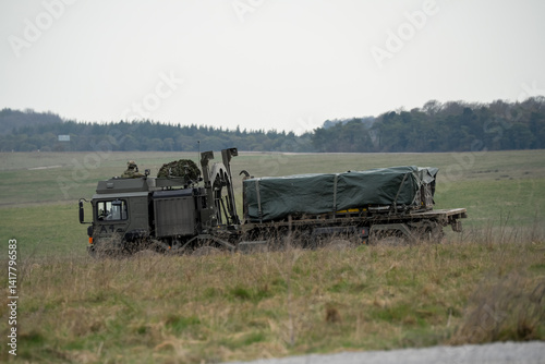 Obraz na płótnie Soldier lookout in the cab of British army MAN SV HX 8x8 eight wheeled logistics truck carrying supplies across countryside w salonie