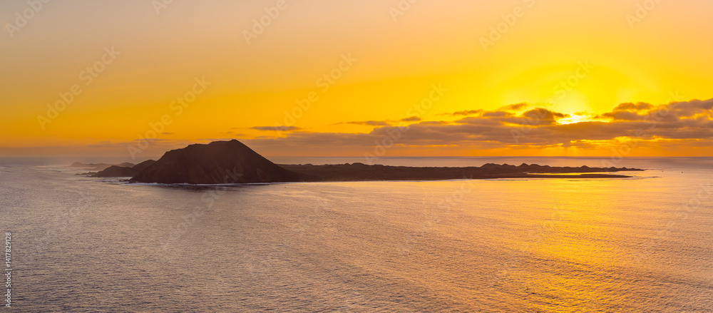 Fototapeta premium Spectacular golden hour sun rise image of the view over the volcanic island Isla de Lobos, near Corralejo, Fuerteventura, Canary Islands Spain
