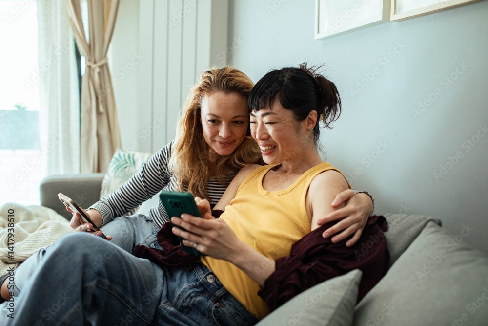 Lesbian couple relaxing on couch with smartphone at home