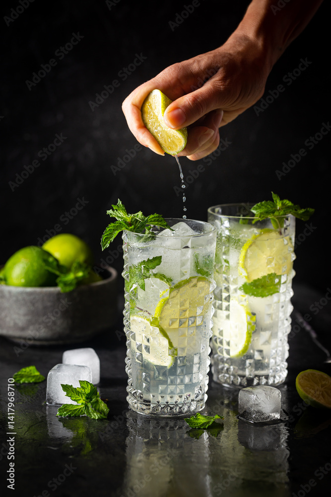 Glass of iced lemonade with lime and mint, cold summer drink on dark background