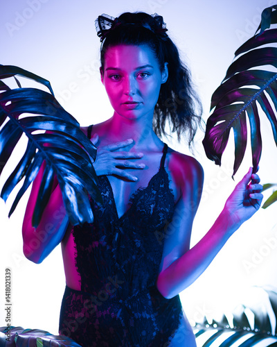 A sensual woman in black lace lingerie poses amidst tropical leaves, illuminated by vibrant neon lighting. The image highlights her seductive expression and mysterious vibe, perfect for luxury
