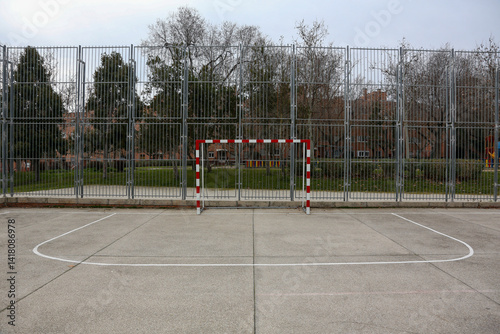 Red and white indoor soccer goal on an outdoor court in a park in Madrid.