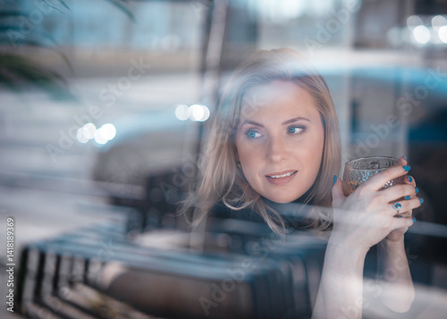 Thoughtful Woman Looking Through Window While Holding a Glass 