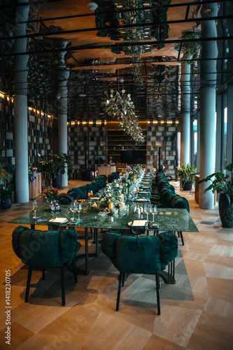 Luxurious dining room featuring a long table with elegant floral centerpieces, green cushioned chairs, and ambient decorative lighting, ideal for upscale dining experiences or events.