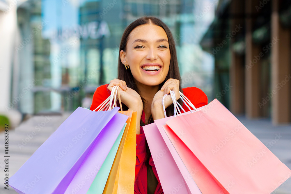 Seasonal sales. Joyful lady after successful shopping holding colorful shopper bags and smiling at camera, standing outdoors in front of shopping mall Seasonal sales. Joyful lady after successful shopping holding colorful shopper bags and smiling at camera, standing outdoors in front of shopping mall
