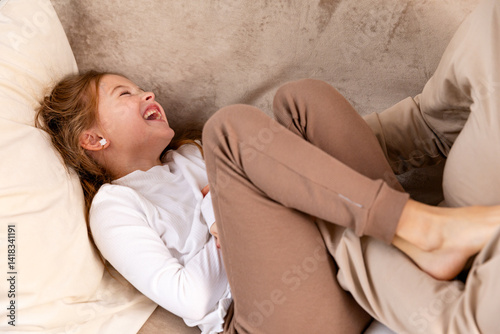 Obraz na płótnie Close up hands of mom tickling kid daughter, laughing together on couch. Cheerful mother playing funny game with little cute girl at home, having fun, relaxing. Happy family. High quality photo w salonie