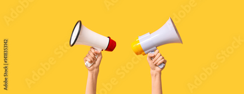 Hands holding megaphones on yellow background