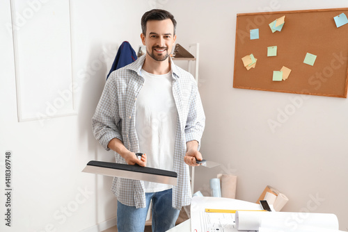 Young man with putty knife ...