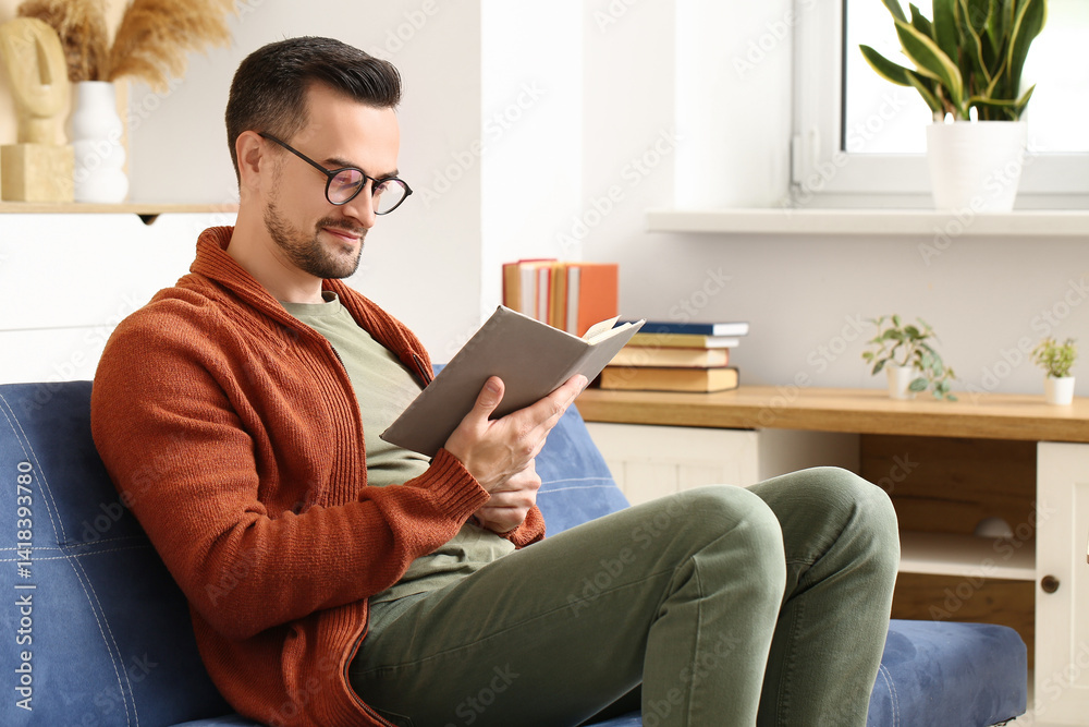 Handsome man reading book on sofa in living room Handsome man reading book on sofa in living room