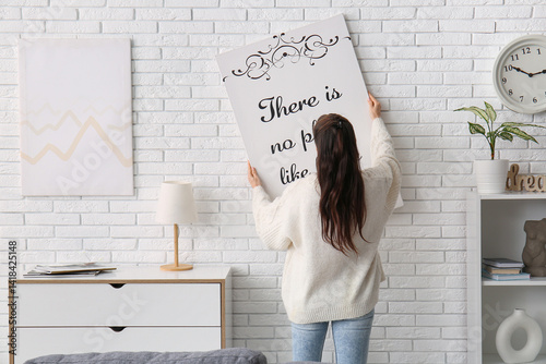 Young woman hanging poster ...