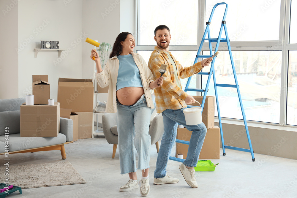 Happy pregnant couple with paint tools during repair in their new house