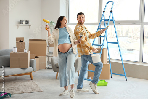 Obraz na płótnie Happy pregnant couple with paint tools during repair in their new house w salonie