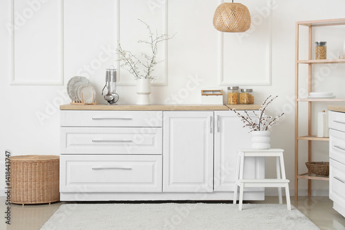 Interior of kitchen with shelving unit and blooming branches in vases on counter