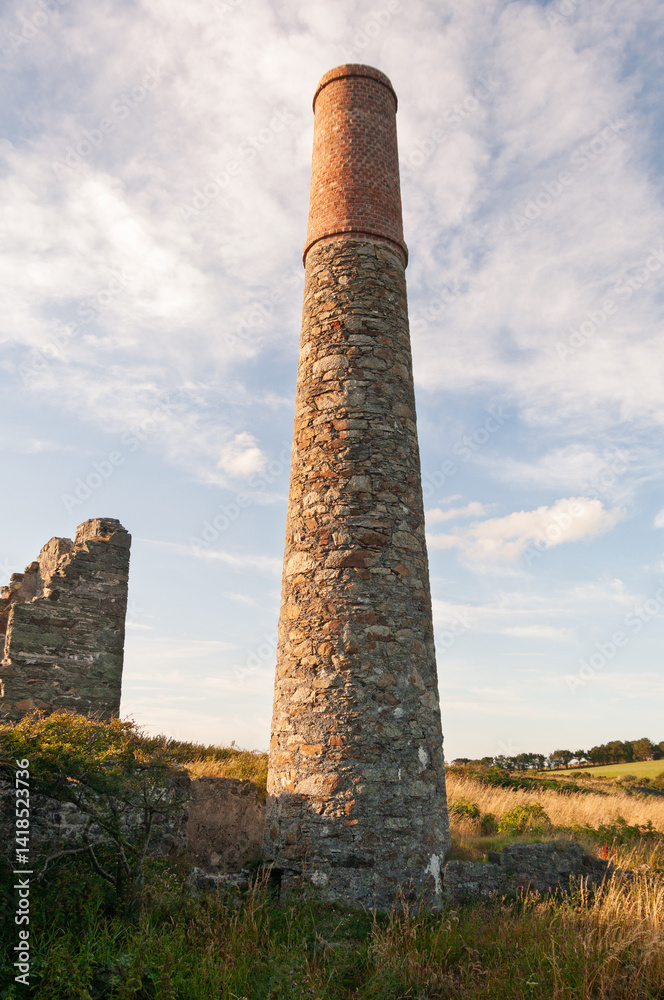 A tall brick tower stands in a field with a cloudy sky in the background A tall brick tower stands in a field with a cloudy sky in the background