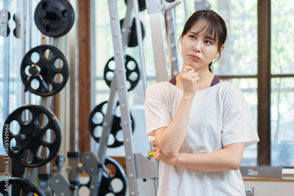 スポーツジムで考え事をする女性