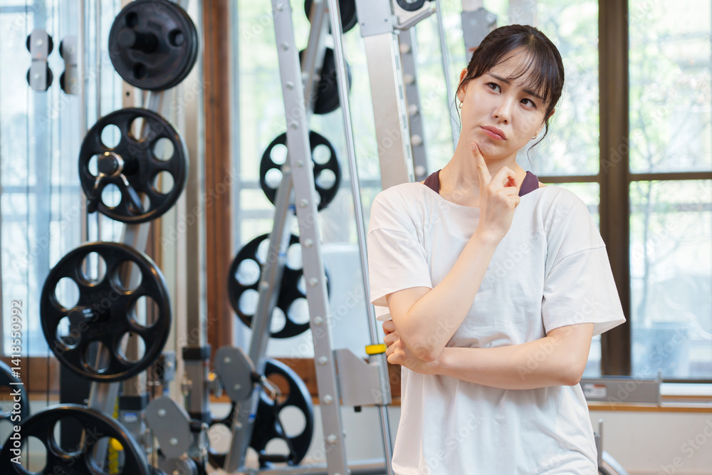 スポーツジムで考え事をする女性