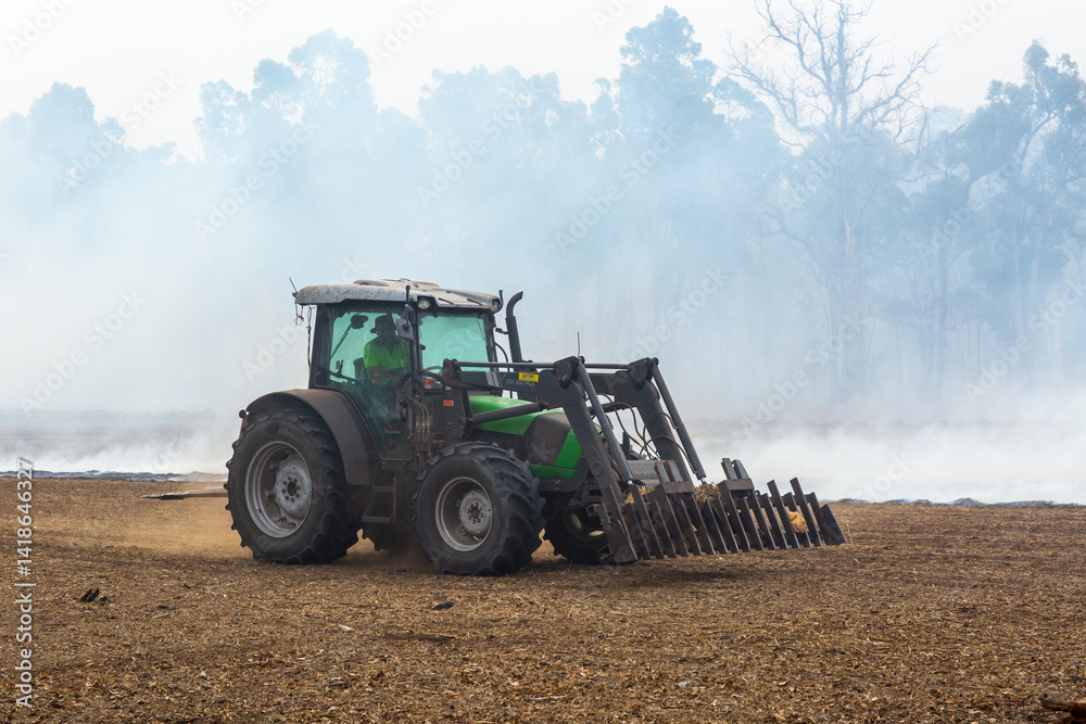 Tractor with rake attachment in front of smoke Tractor with rake attachment in front of smoke