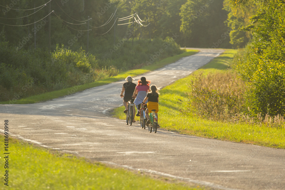 Fototapeta premium Group Cycling Along a Scenic Road During a Sunny Summer Day