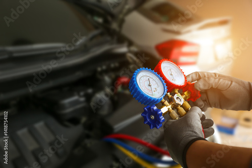 Car mechanic repairman holding air refrigerant meter manifold gauge for car care maintenance services and check air conditioner system heat problem and fix repairing and filling refrigerant.
