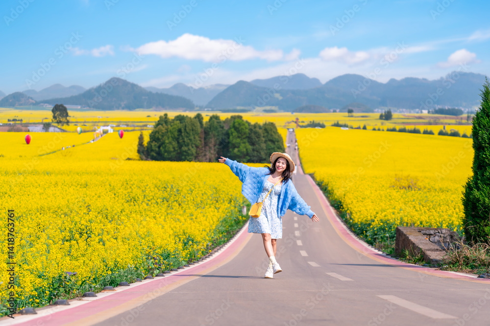 Fototapeta premium Young happy woman tourist enjoying the canola fields while traveling in Luoping, China