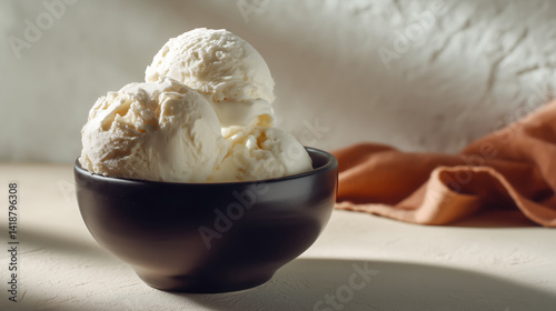 Obraz na płótnie Three scoops of white ice cream in a black bowl on a textured surface. w salonie