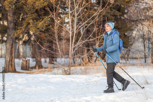Banner mature woman walking in winter park with Nordic walking poles enjoying fresh air and active lifestyle with space for text. health concept, fitness club, winter sports.