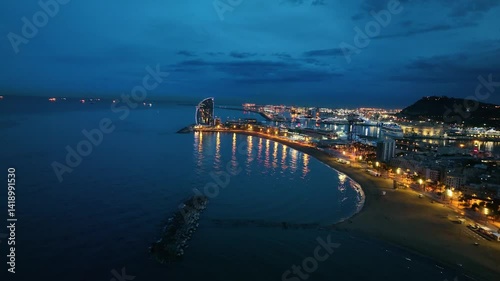 Aerial view of illuminated Barcelona beach and city skyline at blue hour
