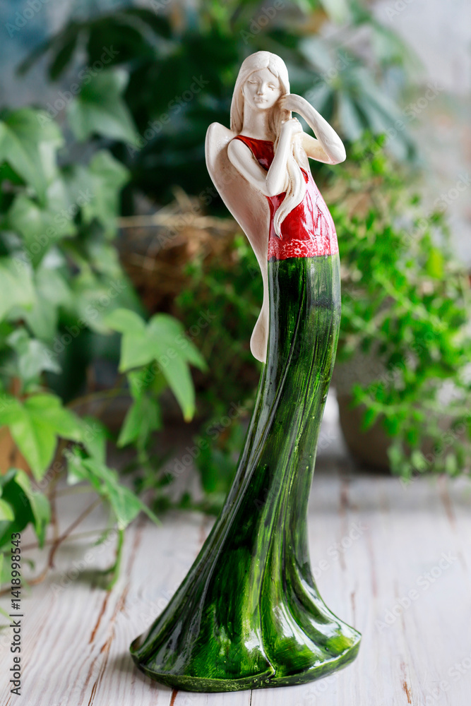 Beautiful figurine of an angel in green dress on the table.