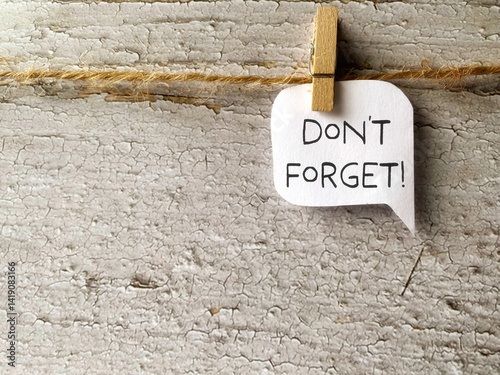 Saying don't forget written on hanging speech bubble background. Stock photo.