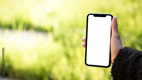 Main féminine tenant un smartphone avec un écran blanc vierge dans le jardin – modèle de maquette avec incrustation mockup Bannière