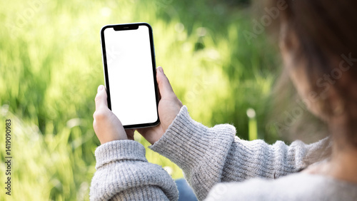 Photography Main féminine tenant un smartphone avec un écran blanc vierge dans le jardin – m