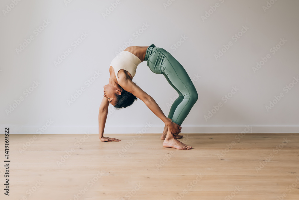 Obraz premium Young woman practicing yoga bridge pose on wooden floor