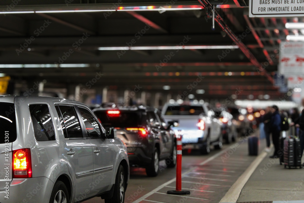 Naklejka premium An airport terminal arrival pick-up area outside with a line of vehicles. blurred people are waiting with luggage. evening background with bokeh light effect