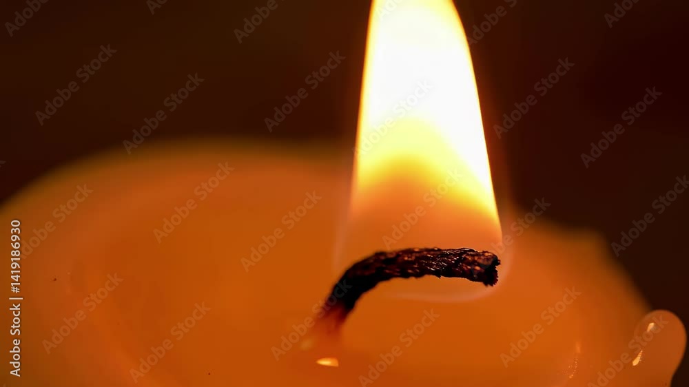 CloseUp of m Flickering Flame from Lit Candle Against Dark Background  Video. A lit candle with a flame in the middle of it.