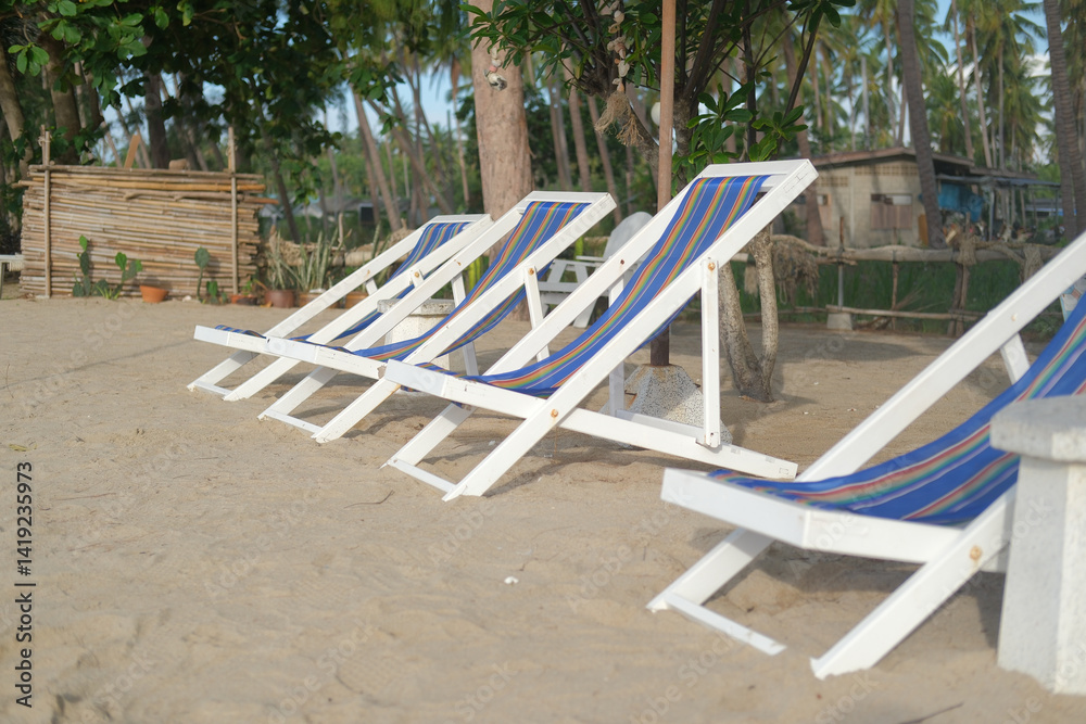 Relaxing summer beach scene with white lounge chairs lined up on sandy shore under palm trees inviting tranquility Relaxing summer beach scene with white lounge chairs lined up on sandy shore under palm trees inviting tranquility