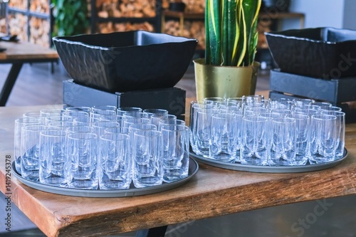 Identical clean transparent water glasses stacked in trays on a table, served for event in restaurant.