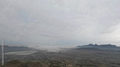 Fog spreads in the valley on a gray cloudy day. Dark and cold landscape