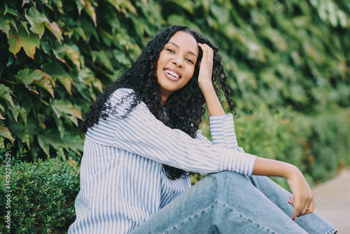 фотографія A Joyful Young Woman Sitting Peacefully in Nature Surrounded by a Lush Greenery