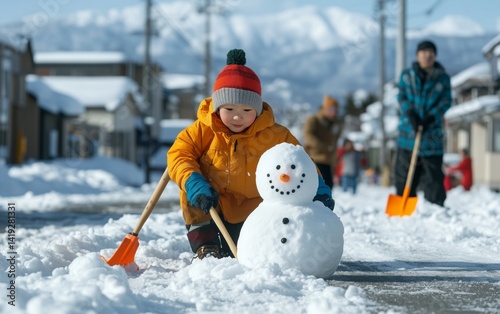 A Child Creates a Snowman in a Snowy Winter Day photo