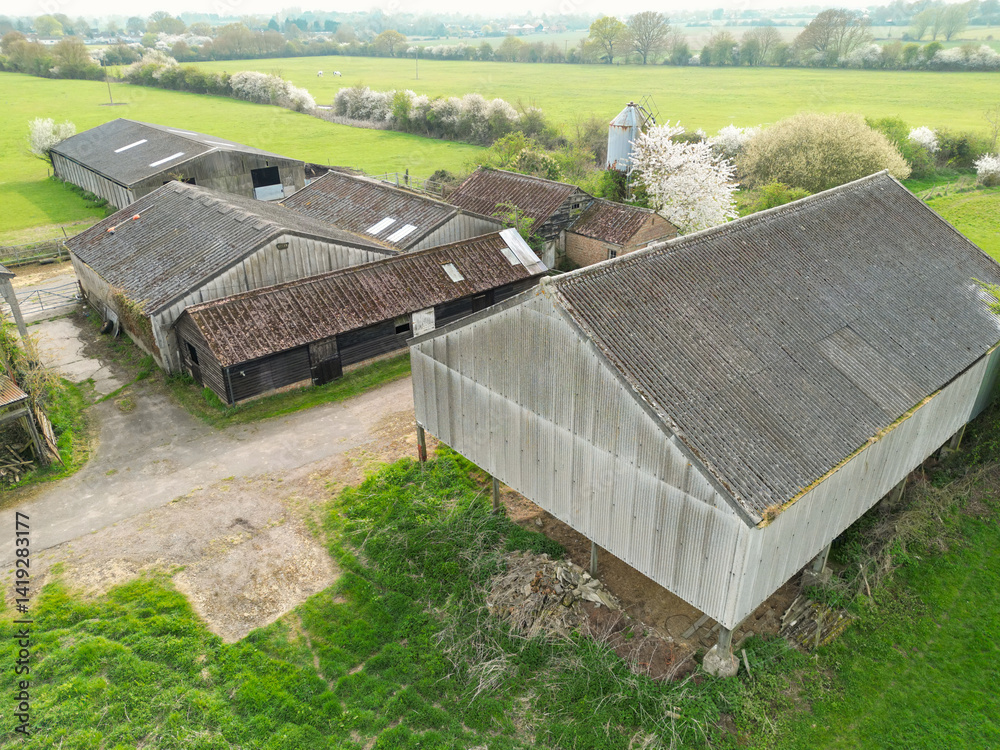 Aerial view of a large and mainly derelict dairy farm seen in rural Britain. Notice the tall grain silo at the back of the image, used to feed the cows when milking.