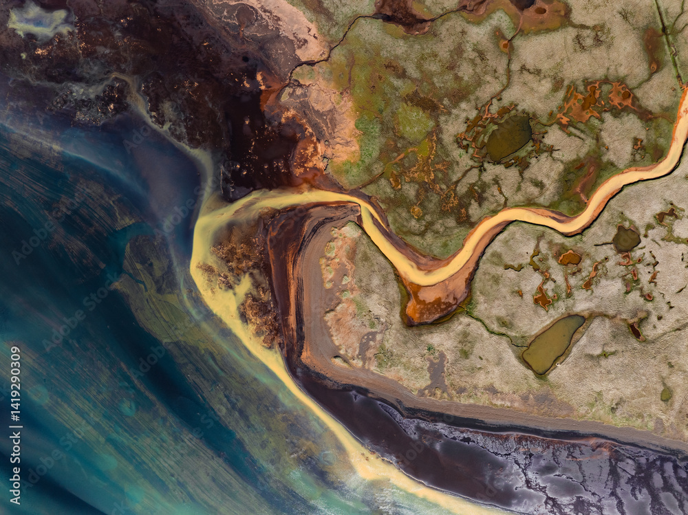 Aerial view of a colorful river delta meeting the sea, with rich earthy tones and vibrant water patterns.