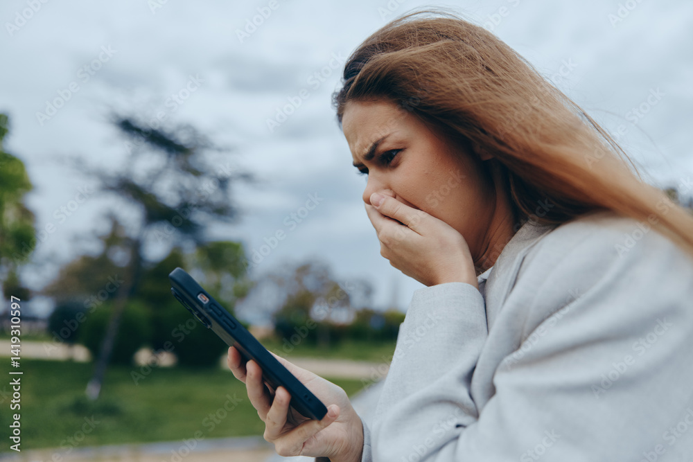 Worried woman looking at phone screen outdoors with anxious expression, emotional stress, casual clothing, cloudy sky background, financial crisis concept