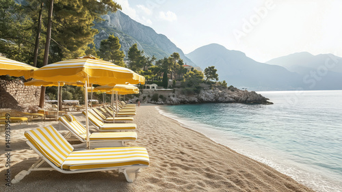Serene beach with yellow striped loungers and umbrellas overlooking tranquil waters. photo