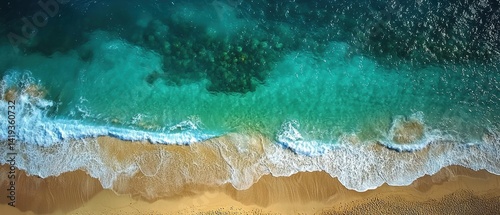 Aerial view of turquoise ocean waves lapping at golden sandy beach