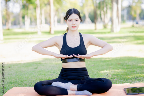 A woman is doing yoga in a garden with trees.