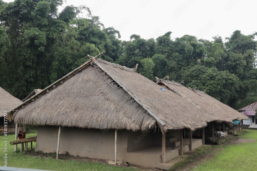 Aerial view of traditional Bale Balaq houses in a village setting in Indonesia, surrounded by lush greenery. Unique longhouse architecture with thatched roofs. Aerial view of traditional Bale Balaq houses in a village setting in Indonesia, surrounded by lush greenery. Unique longhouse architecture with thatched roofs.