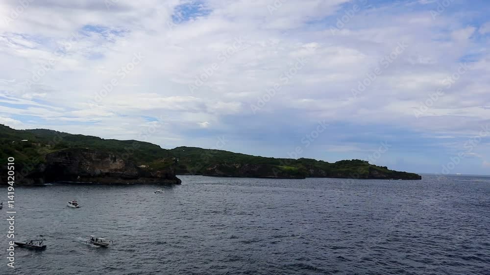 Coastal boats bob in a cove shadowed by cliffs and a sky washed with blue Coastal boats bob in a cove shadowed by cliffs and a sky washed with blue
