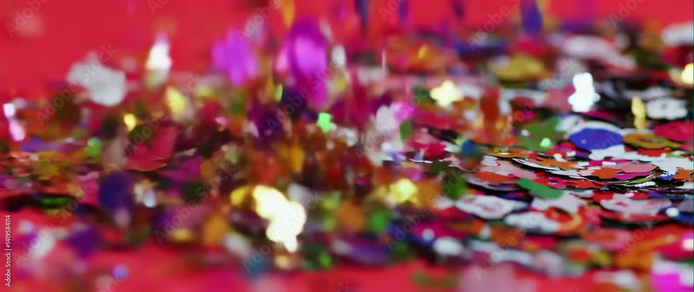 Anamorphic video of Confetti party explosion effect Glitter of festive particles on red background
