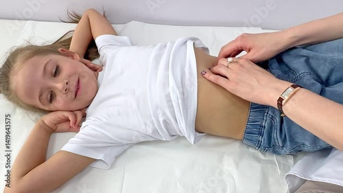 
Top view doctor palpating girl stomach ache in ward. Sick child lying in hospital bed. Female physician examine little patient after therapy in pediatric clinic. Recovering process concept. Footage 
